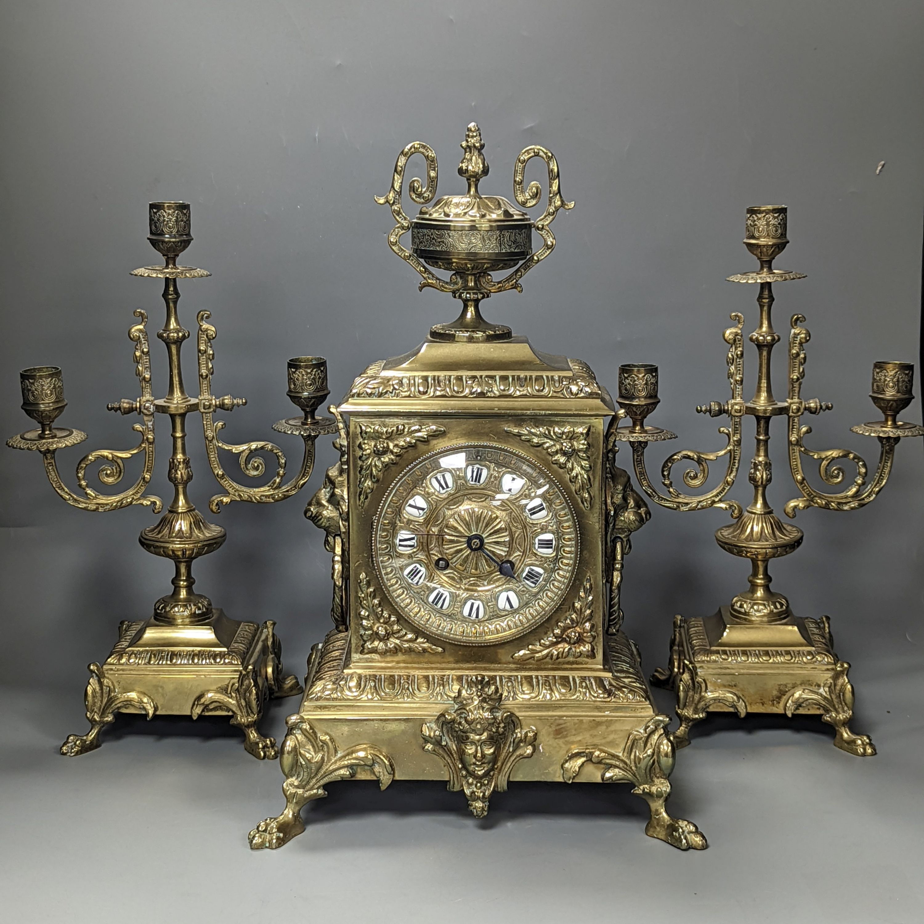 A 19th century French ornate brass clock garniture including a pair of 3 branch candelabra, Clock 42 cms high.